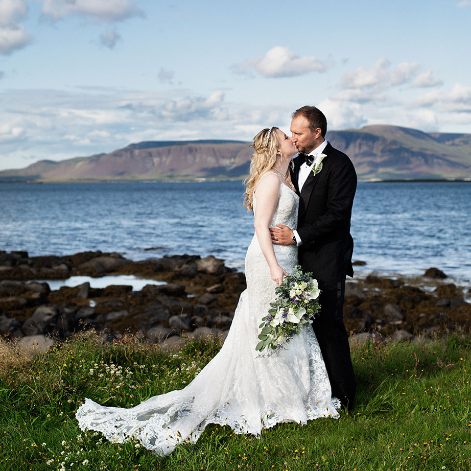Brúðhjónin kyssast i Gróttu með Esju í bakgrunni